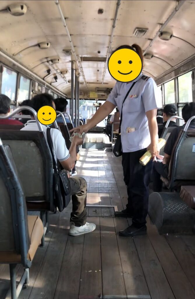現金払いの車掌さんが運賃を集めている、地元路線バスの車内