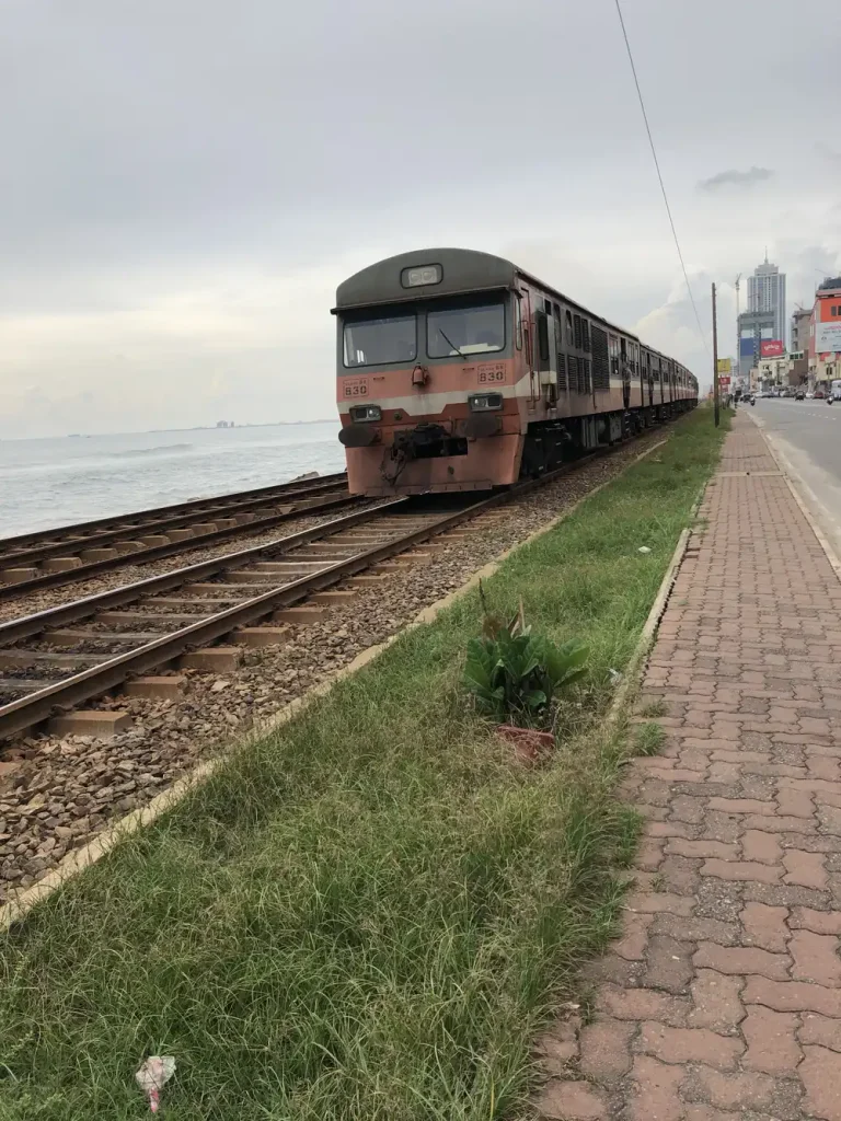 コロンボの海沿い。線路を列車が走り、右手にレンガの歩道と道路が続いている