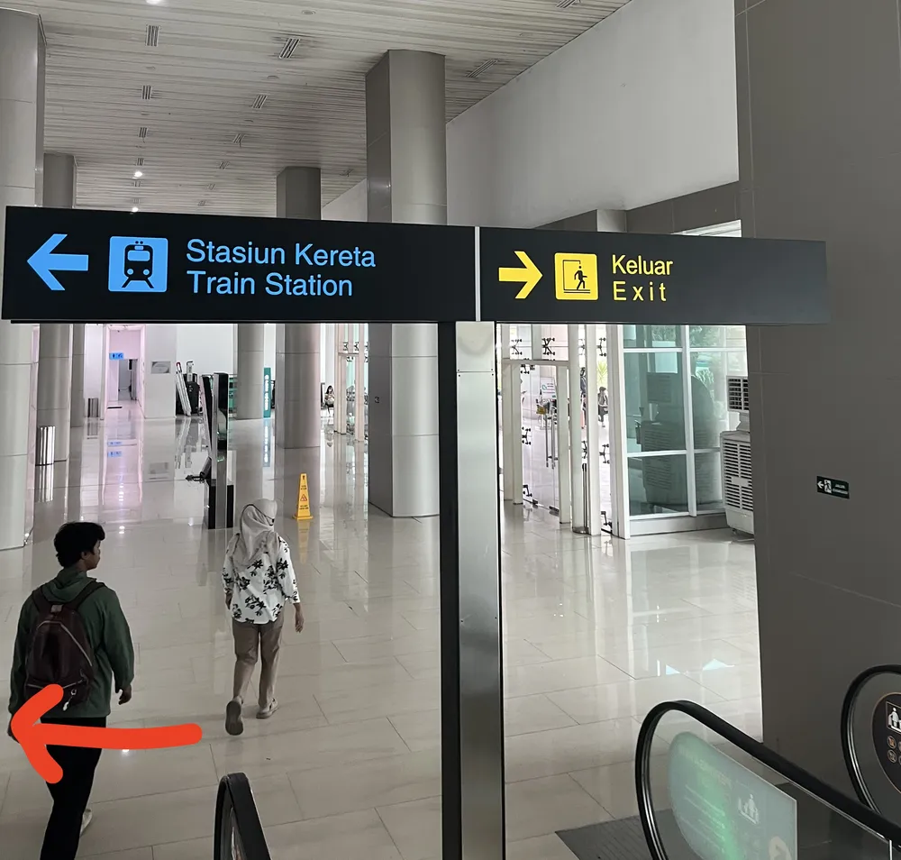 「Stasiun Kereta / Train Station」の案内板と赤い矢印