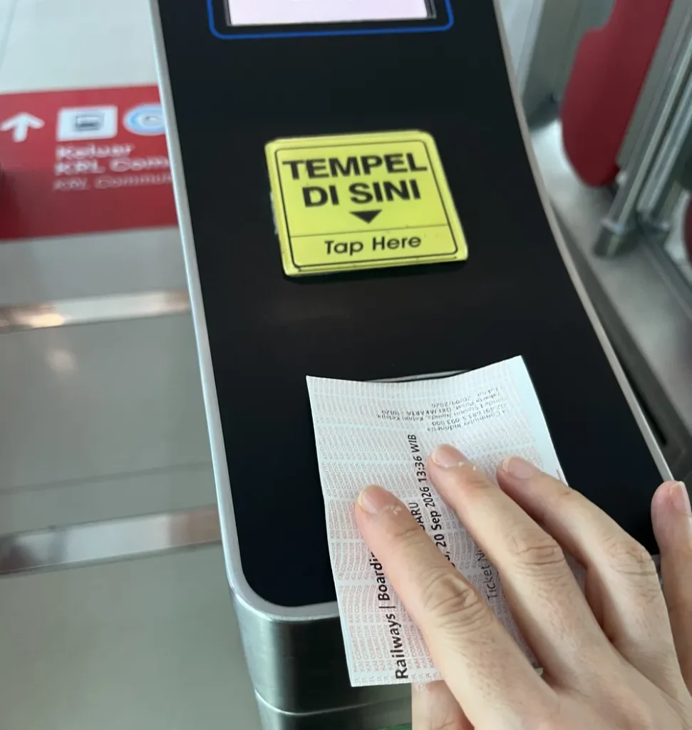 「TEMPEL DI SINI / Tap Here」の読み取り機に乗車券を当てているところ
