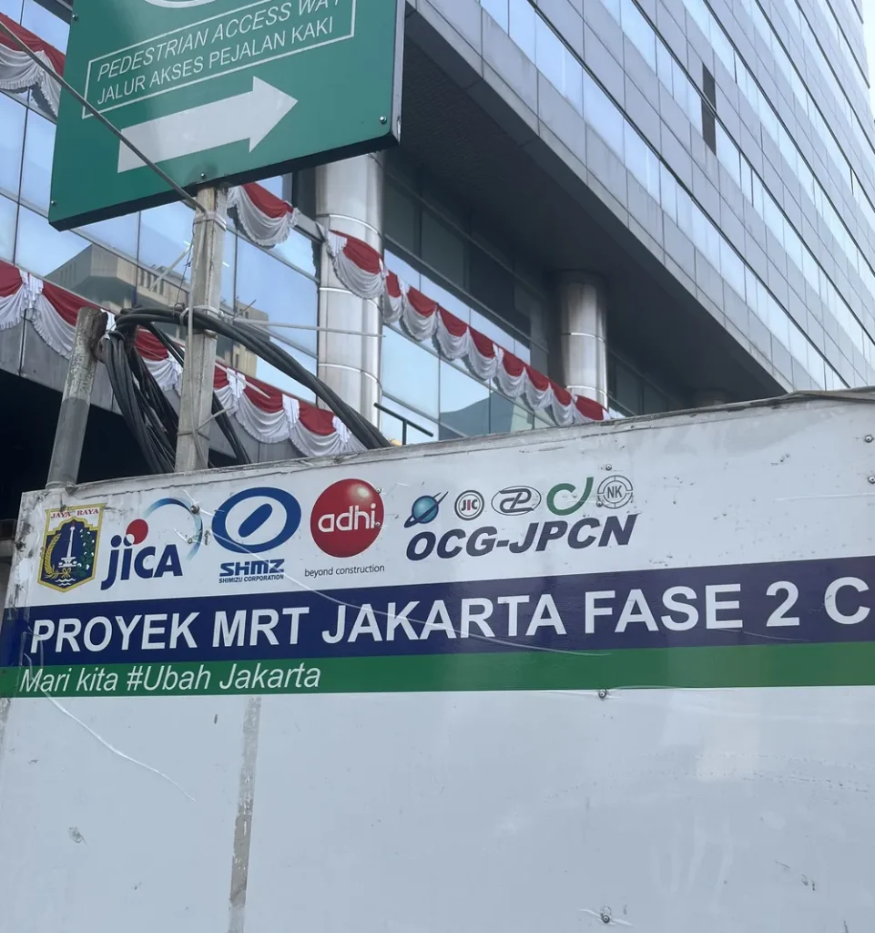 地下鉄の工事現場の看板。「PROYEK MRT JAKARTA FASE 2」の文字とJICAなどのマークが入っている