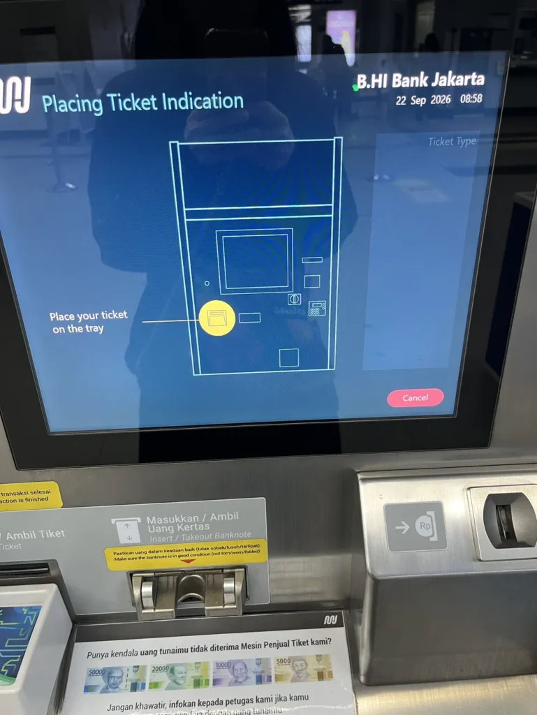 券売機の画面。「Place your ticket on the tray」と表示されている