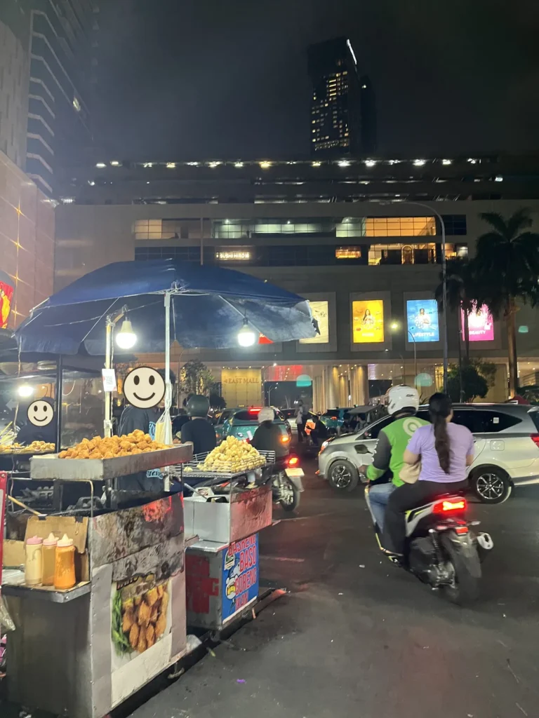夜の大通り。歩道に、揚げ物を並べた屋台が出ている