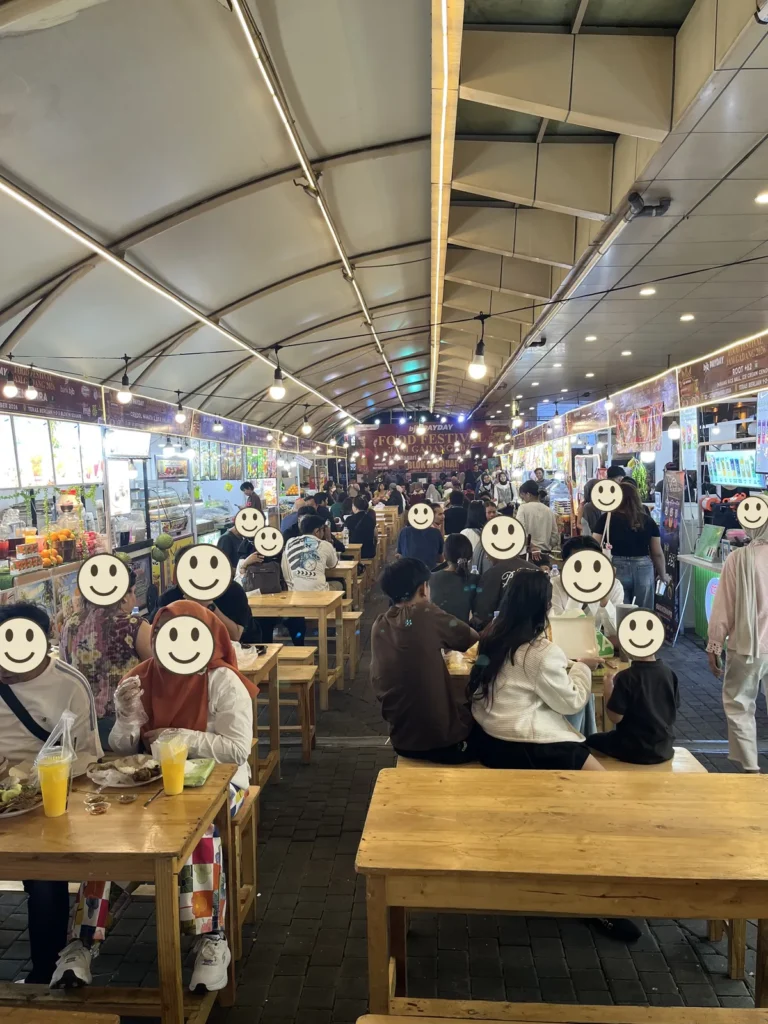 夜、ブロックMスクエアの1階に出る食堂。屋根の下にテーブルが並び、人でにぎわっている