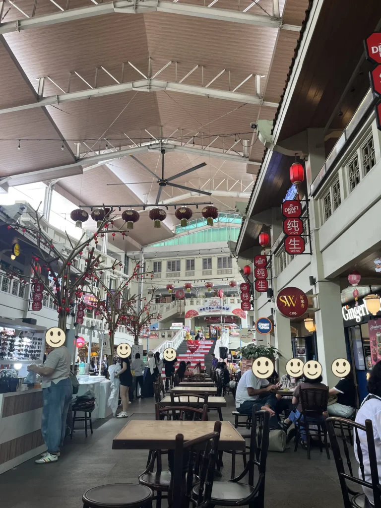 中華街のフードコート。高い天井から赤いちょうちんが下がり、テーブル席で人が食事をしている