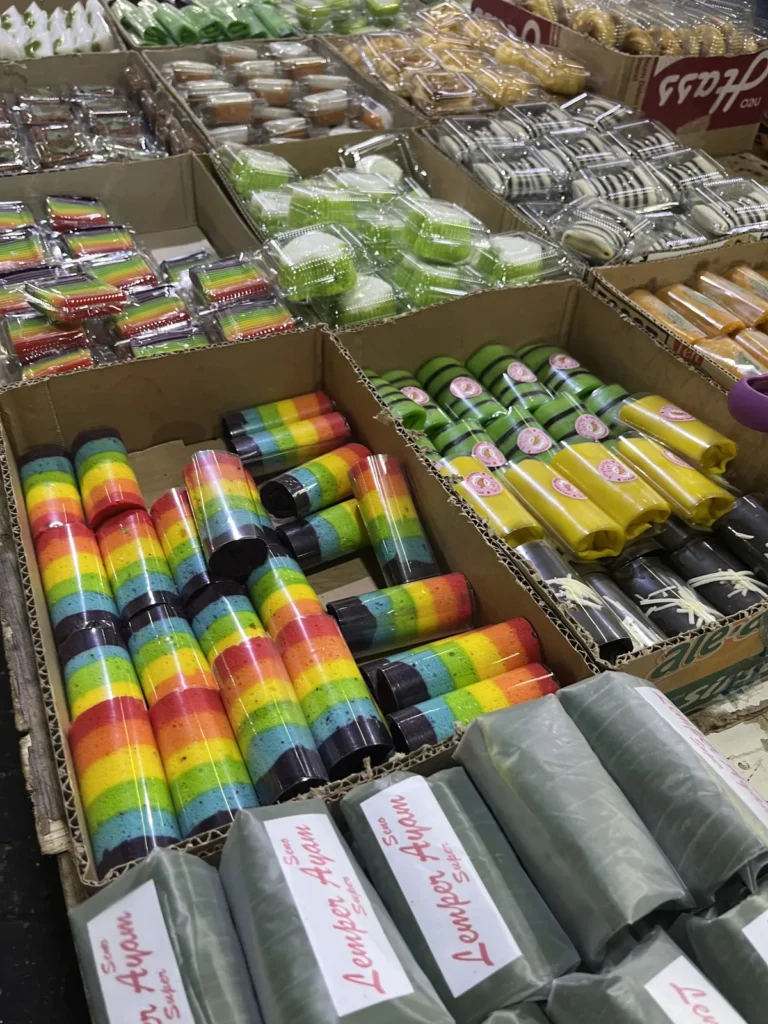 虹色のロールケーキなど、包装されたお菓子が箱に並んでいる